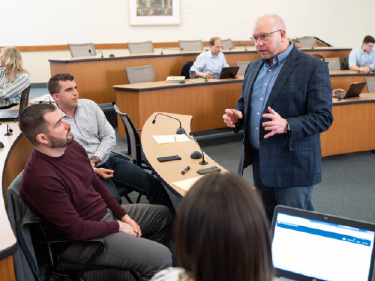 Chris Harper talking to two students in a PMBA class